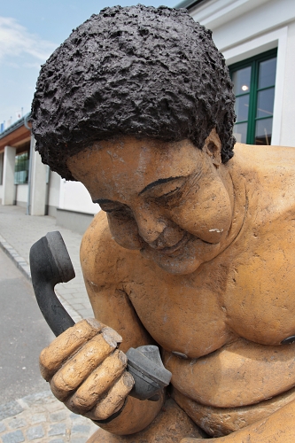 socha nahého kudrnatého muže s telefonem v ruce