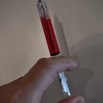 injekční stříkačka s rudou tekutinou uvnitř - propiska