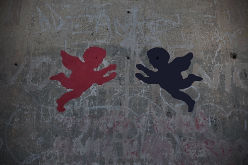 červený a černý andílek namalováni na počmárané zdi
