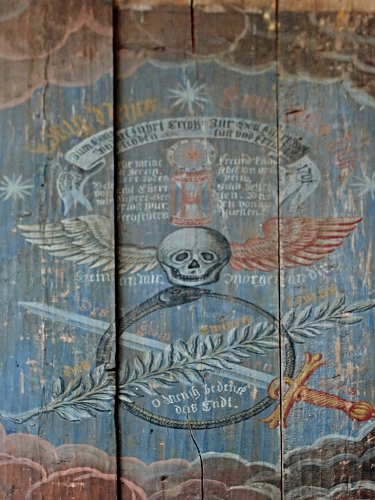 znak na prknech znázorňující lebku, meč a ratolest s nápisy